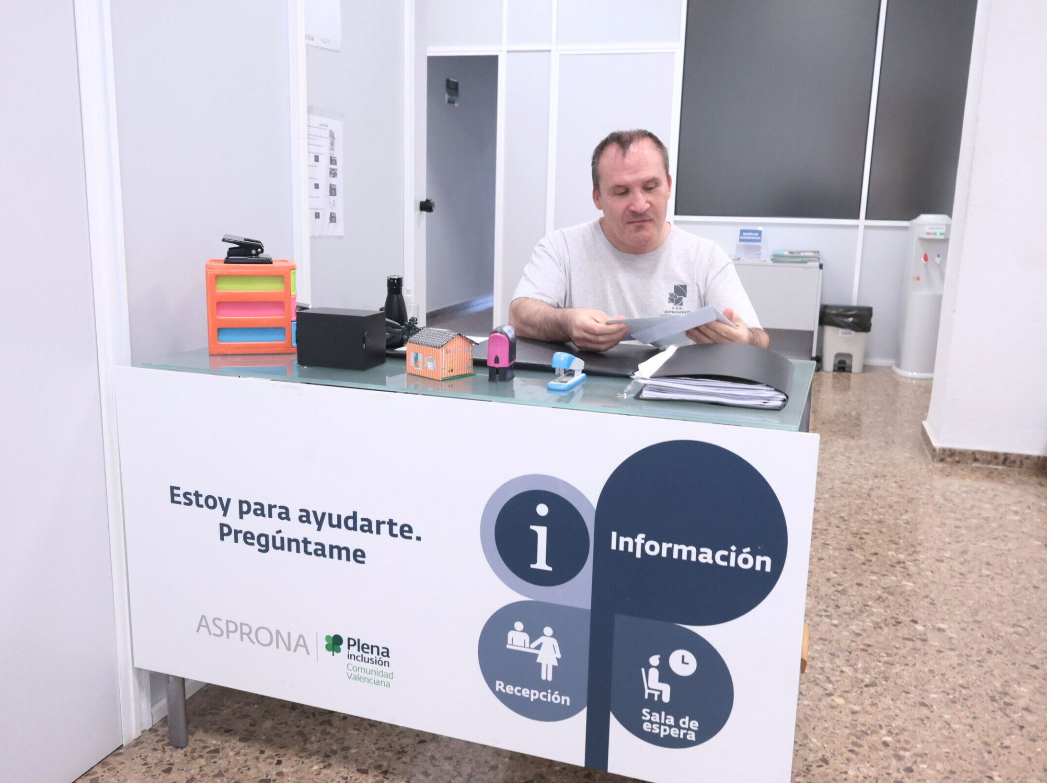 Persona trabajadora sentada frente a un escritorio en una oficina, revisando documentación
