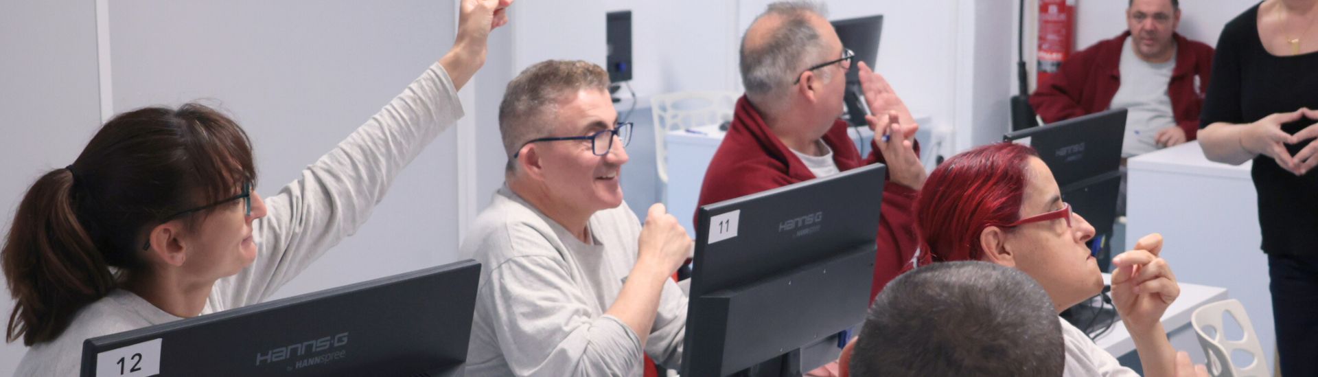 En una charla, un grupo de personas escucha mientras una levanta la mano para hacer una pregunta